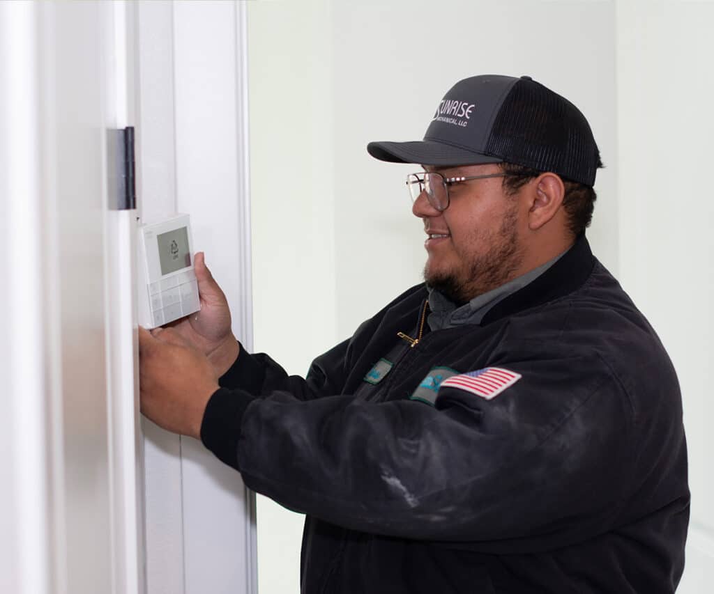 A technician installing a thermostat on a wall.