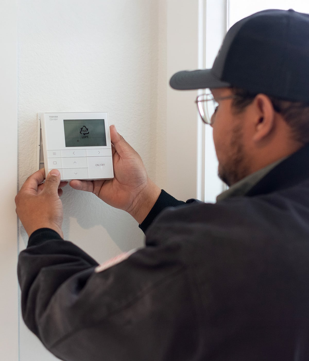A technician installing a thermostat on a wall.