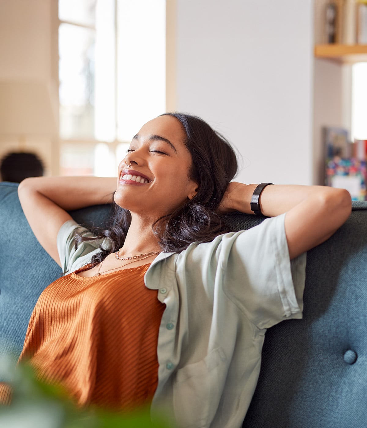A woman relaxing on a sofa, enjoying a moment of peace with a smile