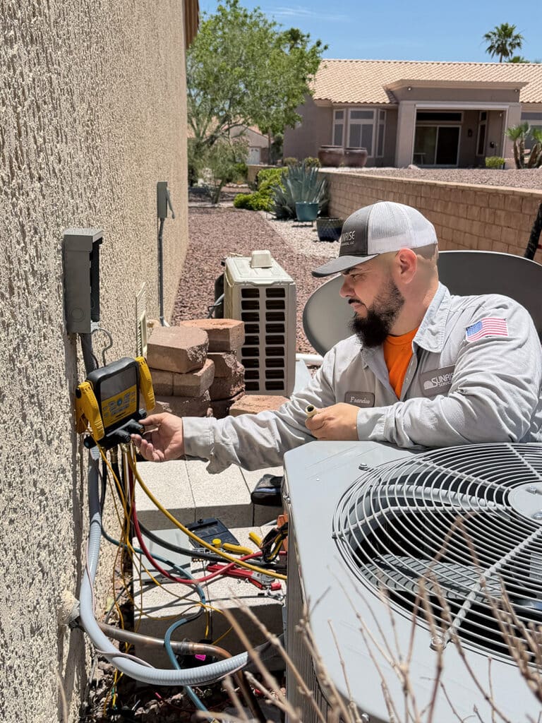 a sunrise hvac technician runs diagnostics on an outdoor air conditioning